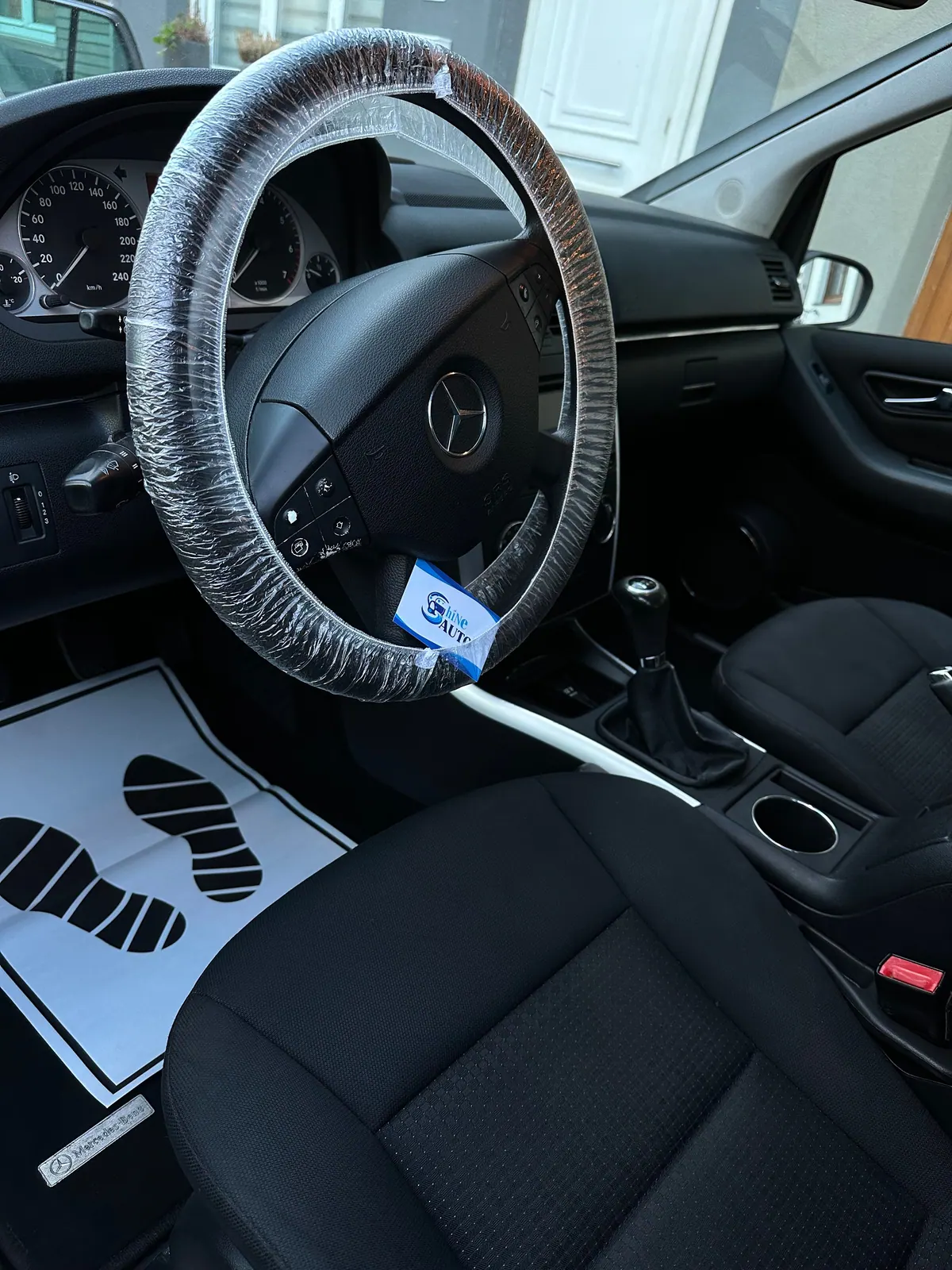 Poste de conduite d'une Mercedes, volant sous film et tapis de protection posé au sol